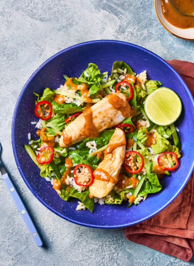 Satay-Style Chicken Rice Salad with Peanut Dressing in a blue bowl from above.