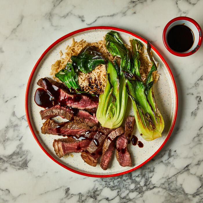 Steak in Black Pepper Sauce Sticky steak in a black pepper sauce on a cream plate with a red rim.